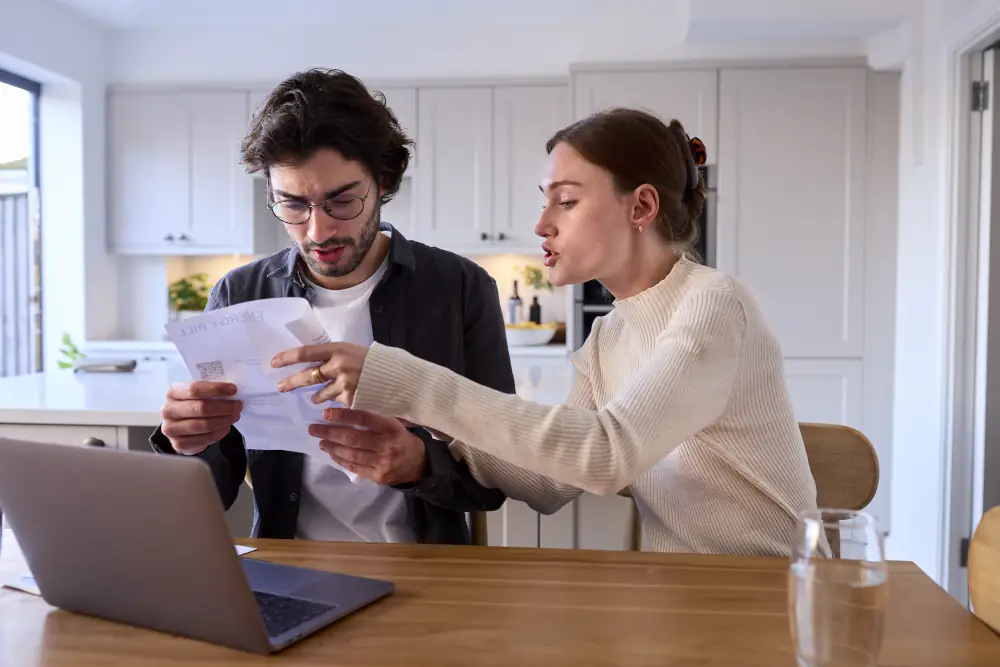 AC repair costs and when to replace - Worried Couple At Home Looking At Laptop Holding Repair Bill